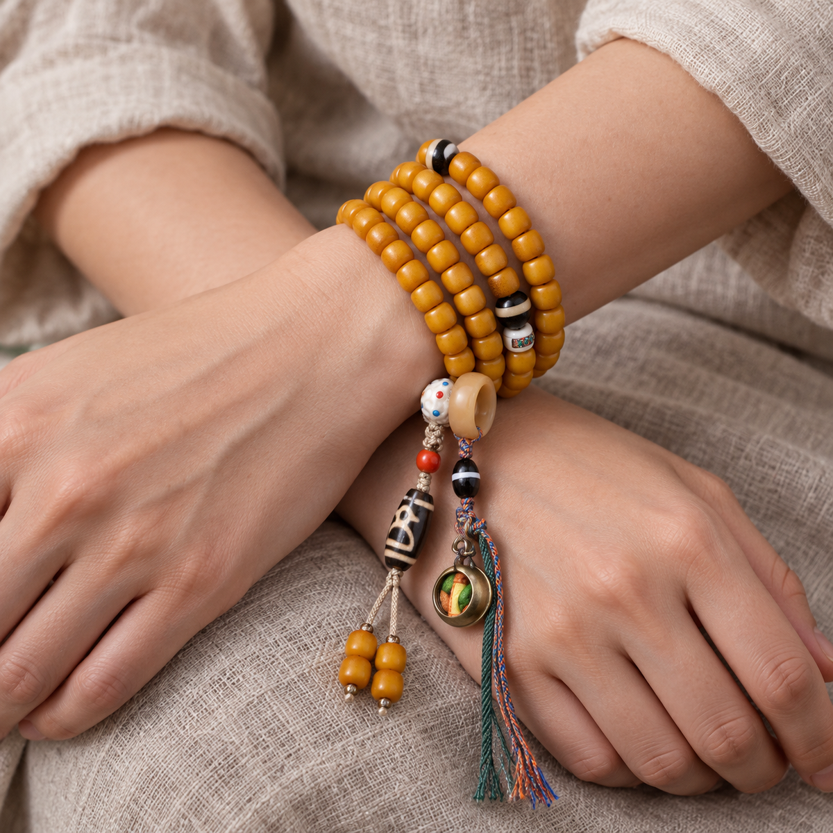 Golden-yellow camel bone 108-bead mala — wrist crossed